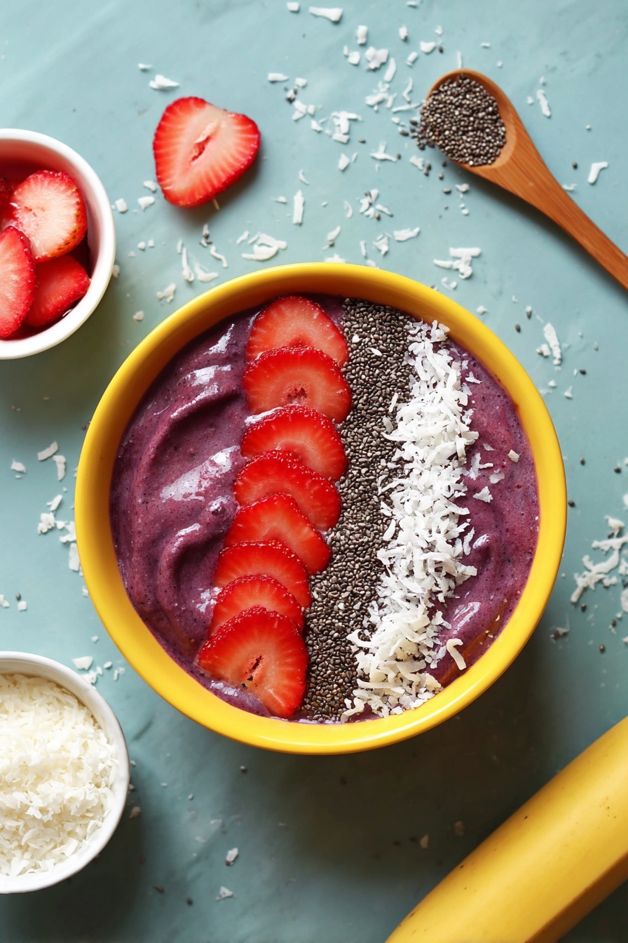 A yellow bowl filled with a thick, purple smoothie forms the base layer, topped with three main toppings arranged neatly in rows from left to right: a white shredded coconut layer with fine texture, a middle row of small black chia seeds, and on the right, five bright red sliced strawberries layered overlapping. The bowl sits on a white marbled surface scattered lightly with shredded coconut pieces. Next to the bowl, there are whole strawberry slices on the left, a small white bowl filled with shredded coconut, a wooden spoon with a small dollop of purple smoothie on the right, and a yellow banana at the bottom edge of the image. The photo taken with an iphone --ar 2:3 --v 7