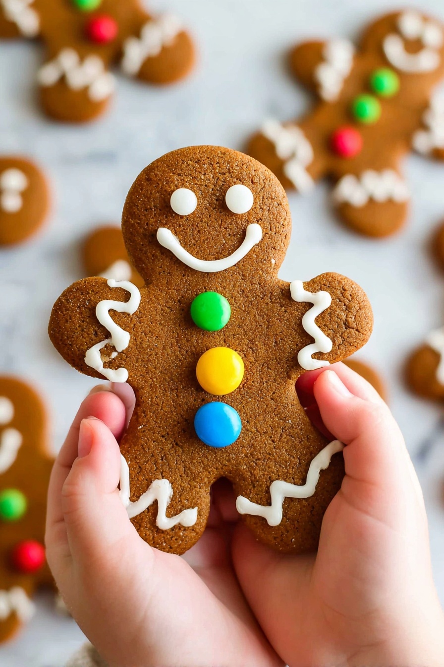A close-up of a gingerbread cookie shaped like a gingerbread man is held by two small hands. The cookie has a deep brown color with a slightly rough texture. The gingerbread man has three round buttons in the middle - one blue, one red, and one yellow, each edged with white icing. White icing forms two round eyes and a smiling mouth on the head. The arms and legs are decorated with zigzag white icing lines. In the background, several blurred gingerbread men lay flat on a white marbled surface. photo taken with an iphone --ar 2:3 --v 7