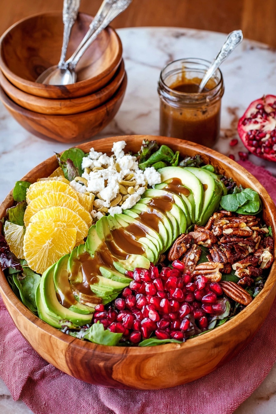 A large wooden bowl filled with a colorful salad placed on a white marbled surface with a pink cloth underneath. The salad has six main layers arranged in sections: dark green leafy base at the bottom, bright yellow citrus slices on the left, white crumbly cheese next to the citrus, green sliced avocado fanned out in the middle with brown dressing drizzled on it, dark brown roasted nuts to the right, and bright red pomegranate seeds near the center. Behind the bowl, there are stacked wooden bowls with metal spoons inside and a small glass jar with a spoon, containing brown dressing. photo taken with an iphone --ar 2:3 --v 7