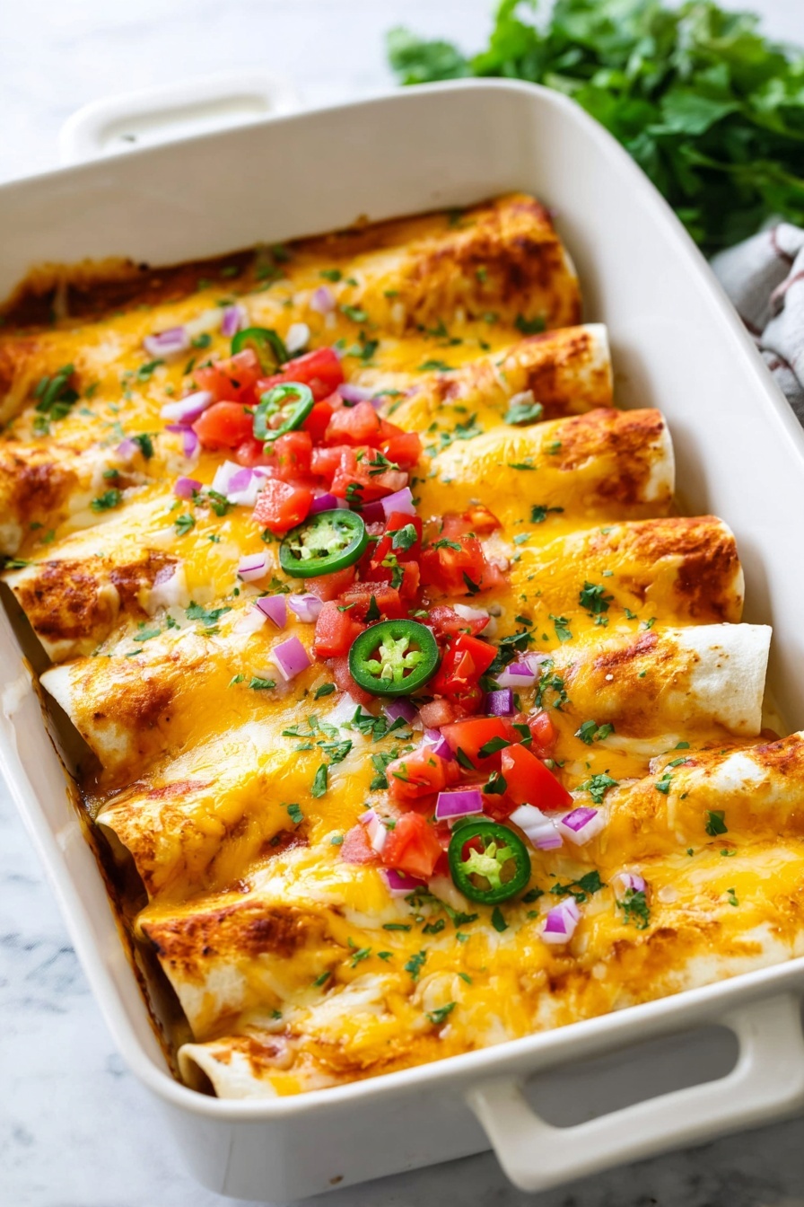A white baking dish filled with five rolled enchiladas arranged side by side, each covered with melted yellow and white cheese that has a slightly browned texture. The enchiladas are topped with small, bright red tomato pieces, finely chopped purple onion, and green jalapeño slices in the center. Small bits of finely chopped green herbs are sprinkled evenly over the cheese. The dish is placed on a white marbled surface, with some green herbs blurred in the background. Photo taken with an iphone --ar 2:3 --v 7