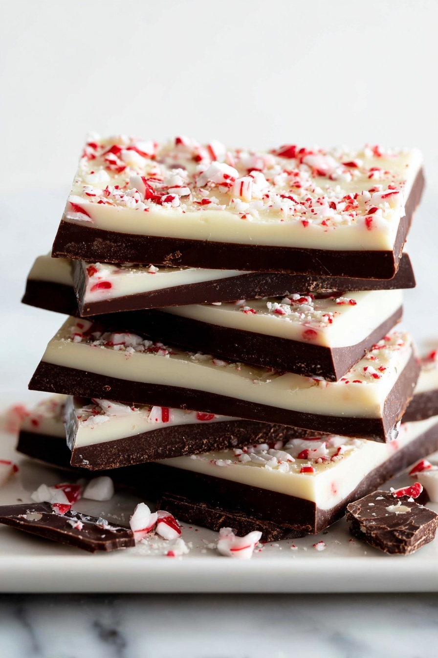 A stack of five rectangular peppermint bark pieces sits on a white plate, each piece showing three main layers: a dark chocolate middle layer sandwiched between two thick, smooth white chocolate layers, the top layer sprinkled with small red and white peppermint candy bits. The bark pieces have a slightly uneven, rustic edge, and there are broken pieces of bark around the plate. The scene is set against a white marbled surface with soft natural light highlighting the glossy texture of the chocolate layers. Photo taken with an iphone --ar 2:3 --v 7