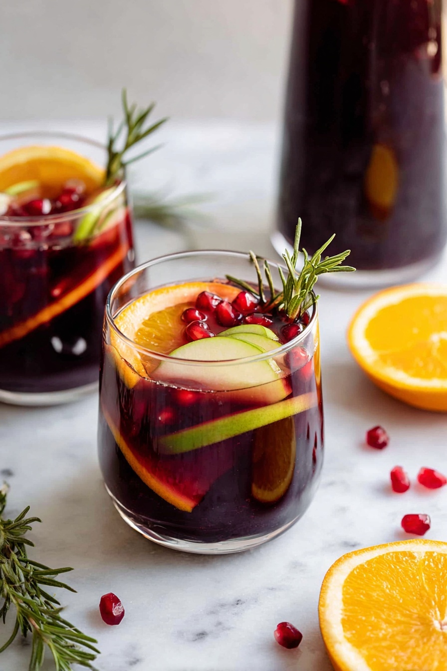 A clear glass bottle filled halfway with dark red liquid stands on a white marbled round board. In front of the bottle, there are two short clear glasses with the same dark red drink. Each glass has several layers: at the bottom are scattered small red pomegranate seeds, followed by the dark red liquid, and floating on top are slices of orange and light yellow lemon, along with some small green herbs and pomegranate seeds for decoration. Around the glasses on the board, there are more loose pomegranate seeds and a wedge of bright orange fruit. The setting is bright with a clean white marbled background photo taken with an iphone --ar 2:3 --v 7